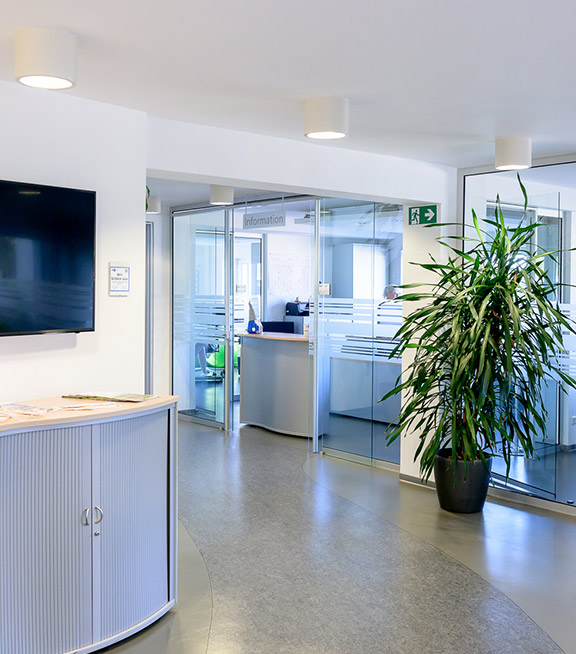 Heller Eingangsbereich der Stadtwerke Friedrichsthal mit modernem Empfangstresen, großem Bildschirm an der Wand und Glastüren zu Büroräumen.